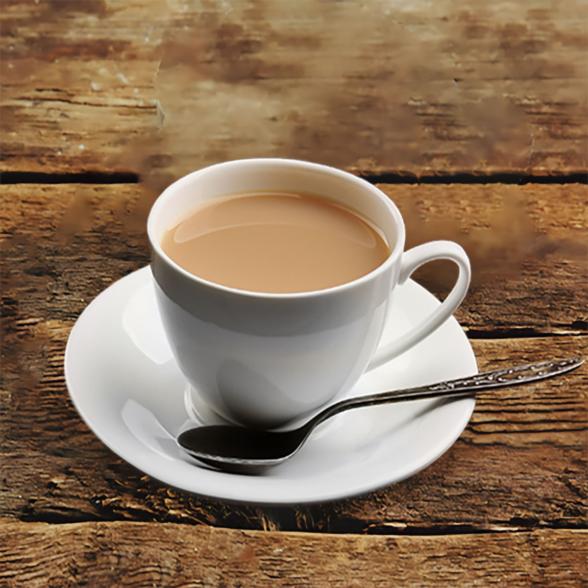 White cup of cafe con leche on a saucer with a spoon on a rustic wooden table.