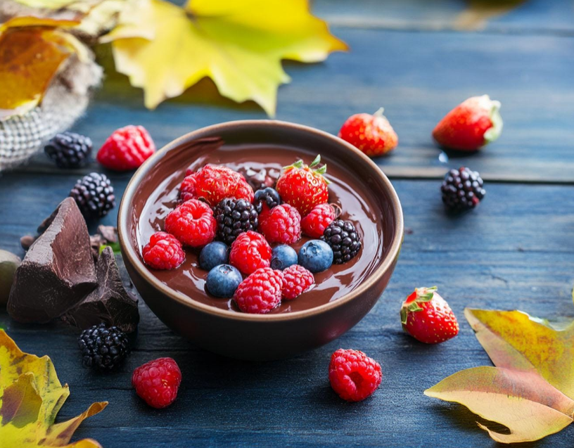 a bowl of chocolate pudding topped with berries and raspberries