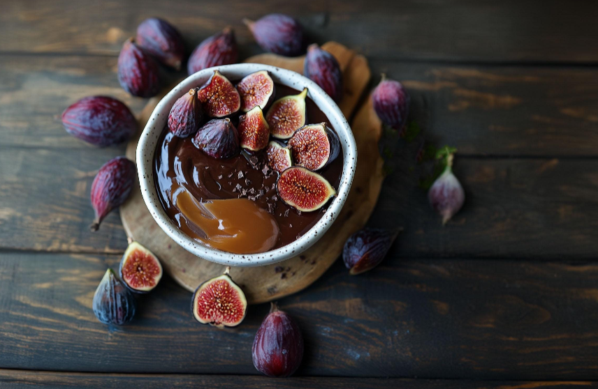 a bowl filled with chocolate and figs on top of a wooden table